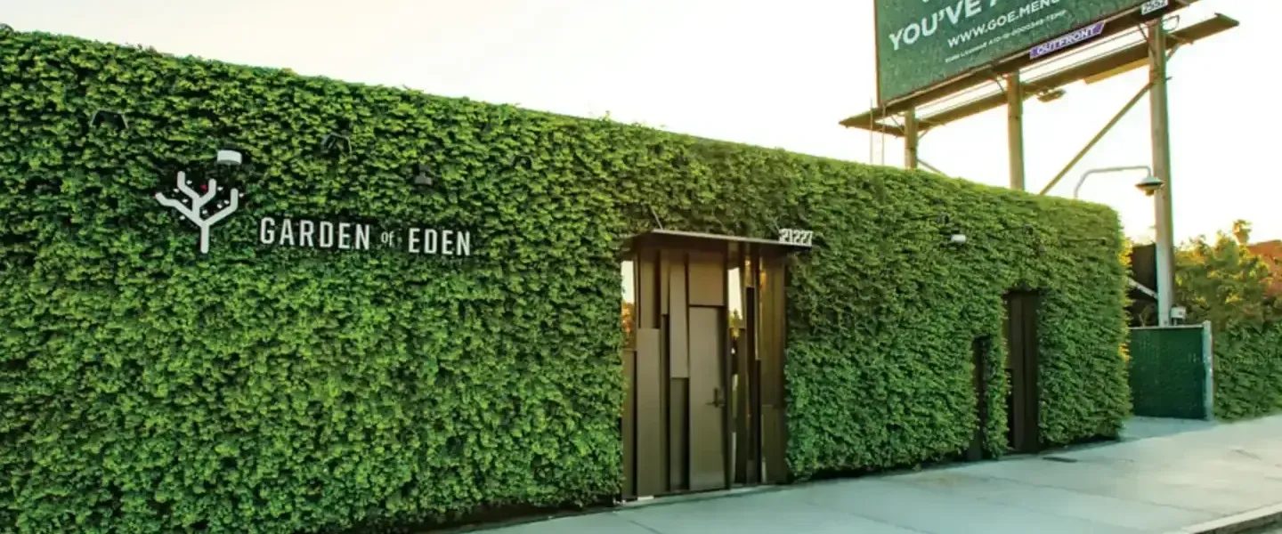 Garden of Eden dispensary building covered in greenery with logo and billboard